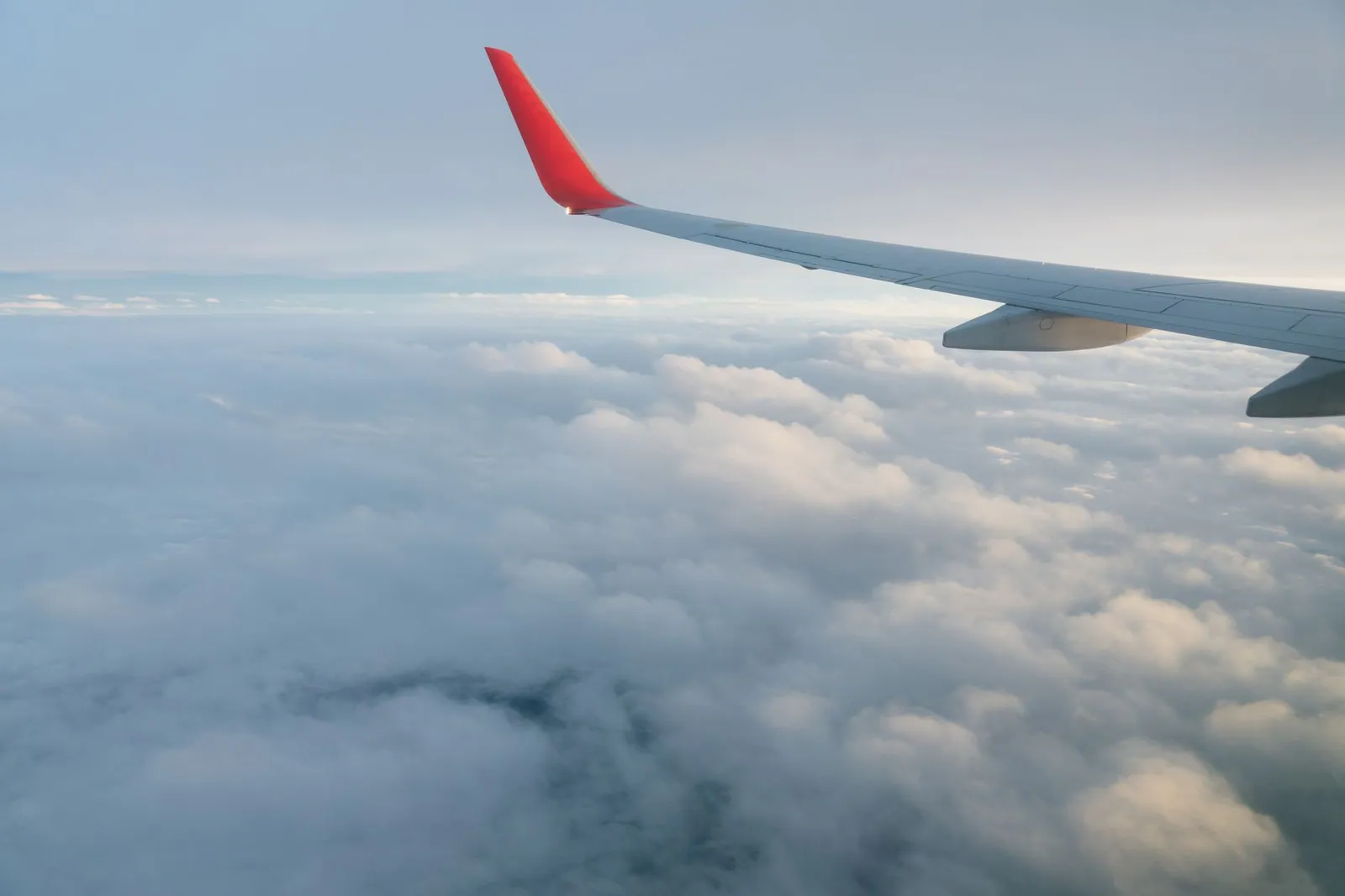 Aircraft wing over clouds seen from a passenger window